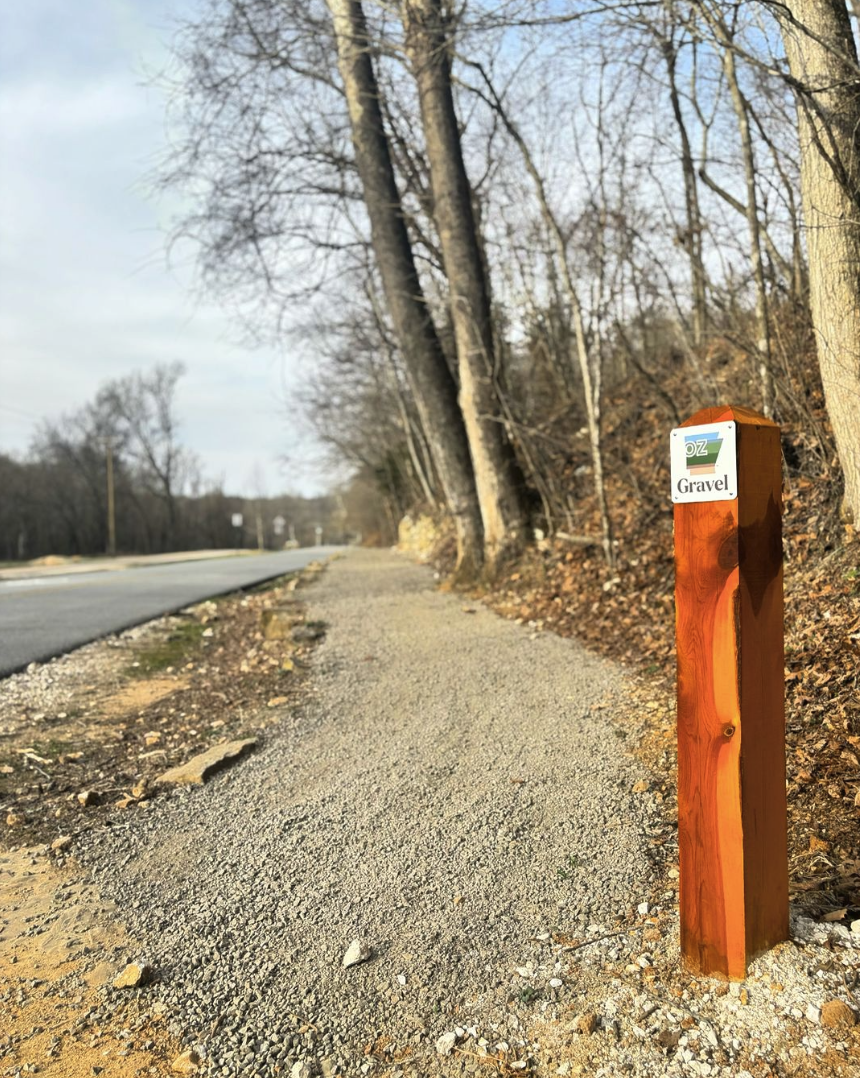 A 3-foot-tall wooden post with an OZ Gravel sign signifying it's a gravel connector.